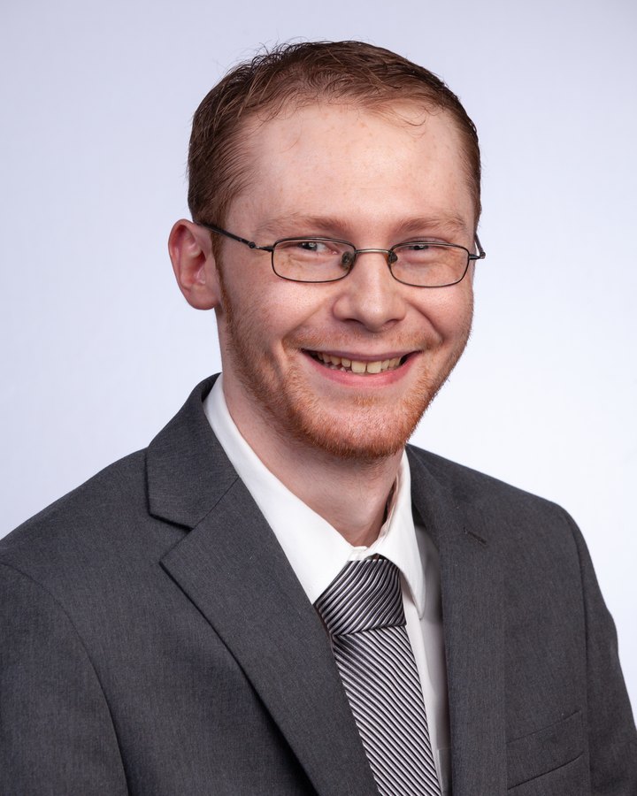 Aaron Robinson, Vice Treasurer of Veterans Resource Alliance, in a grey suit and tie in a professional studio portrait